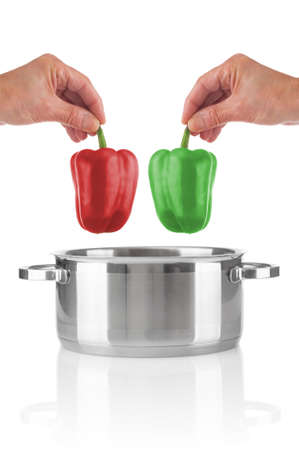Man`s hands throwing red and green peppers in saucepan on white backgroundの写真素材