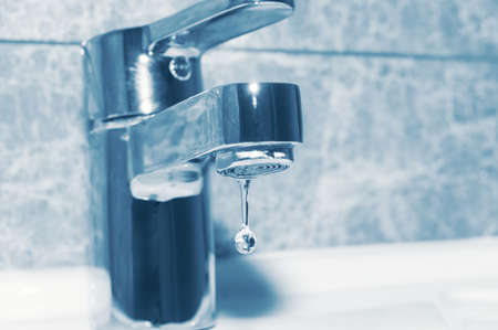 Metal faucet and falling water drop close upの写真素材