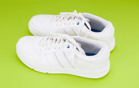 Pair white sport sneakers close up on green backgroundの写真素材