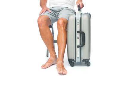 Traveler barefoot man with travel suitcase sitting in a chair on white backgroundの写真素材