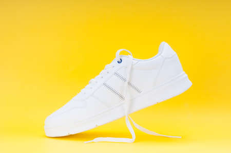White sport sneaker close up on yellow backgroundの写真素材