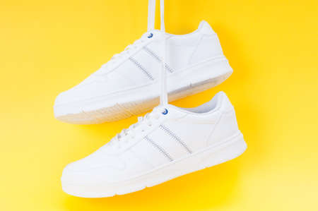 Pair of white sport sneakers close up on yellow backgroundの写真素材