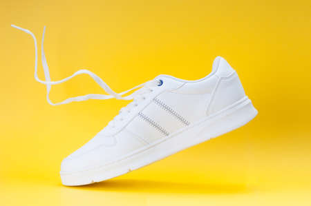 White trendy sneakers close up on yellow backgroundの写真素材