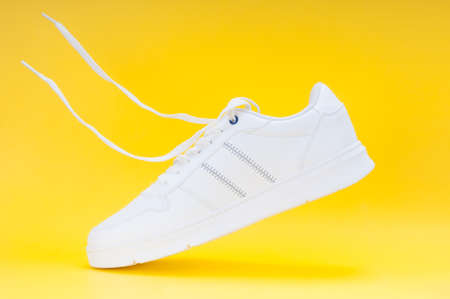 White sport sneakers close up on yellow backgroundの写真素材