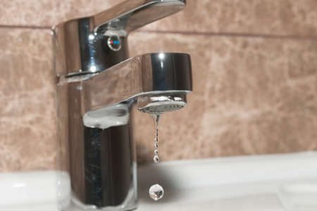 Metal tap and falling water drop close upの写真素材