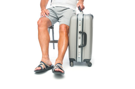 Traveler man in shorts with travel suitcase sitting in a chair on white backgroundの写真素材