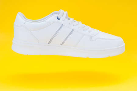 Single white sport sneaker close up on yellow backgroundの写真素材