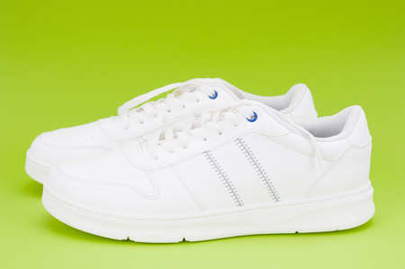Pair white sport sneakers close up on green background