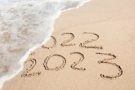 Inscription 2022 and 2023 numbers written on sand. New Year 2023 replace 2022. Concept on the sea beachの写真素材