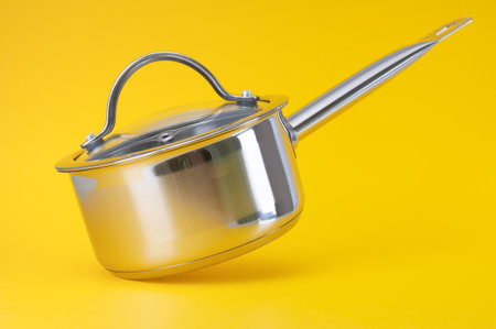 Stainless saucepan with metal lid on a yellow backgroundの写真素材