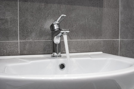Water flowing from chrome tap in a bathroomの写真素材