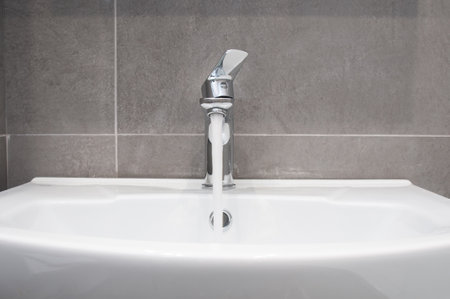 Water flowing from chrome tap in a bathroomの写真素材