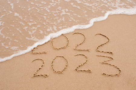 Inscription 2022 and 2023 numbers written on sand. New Year 2023 replace 2022. Concept on the sea...
