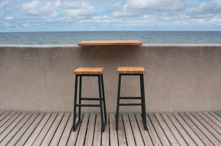 Empty wooden benches along sea coast line under cloudy skyの写真素材