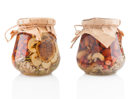 Glass jars with mixed nuts in honey on white backgroundの写真素材
