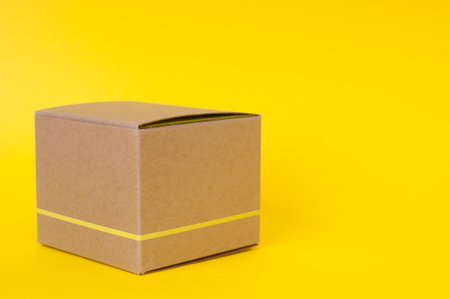 Closed cardboard box on a yellow backgroundの写真素材