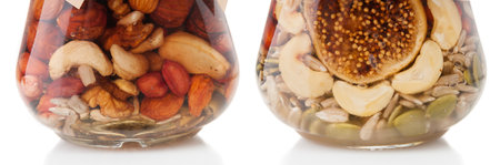 Glass jars with mixed nuts in honey close up on white backgroundの写真素材