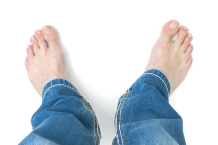 Barefoot man in blue jeans trousers on white backgroundの写真素材