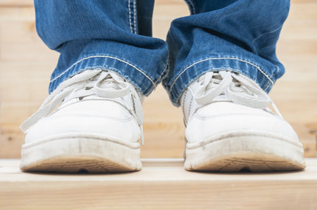 Man legs wearing in jeans and sneakers on wooden backgroundの写真素材