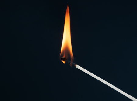 Burning matchstick close up on a dark backgroundの写真素材