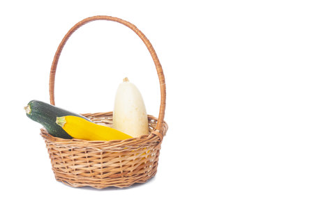 Wicker basket with ripe zucchinis on a white backgroundの写真素材