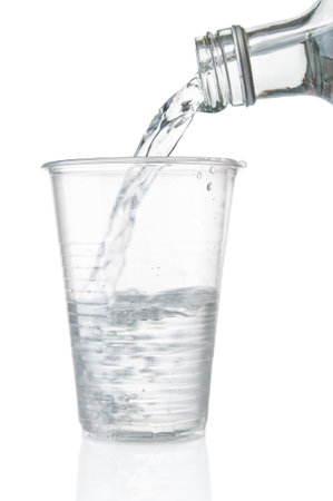 Pouring water into disposable plastic cup on a white backgroundの写真素材