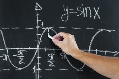 Hand with chalk draws a graph on blackboard close upの写真素材