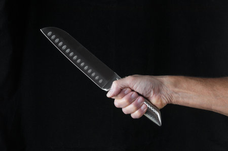 Chef kitchen knife santoku in hand close up on a black backgroundの写真素材