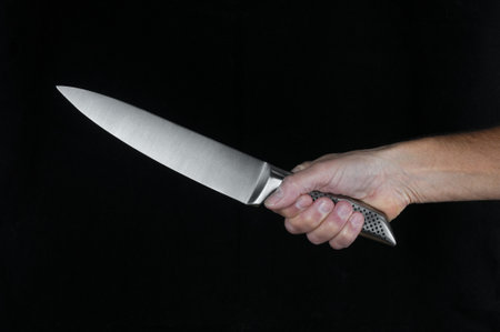Chef kitchen knife in hand close up on a black backgroundの写真素材