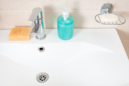 Clean sink with soap and sponge in bathroom