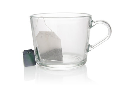 Empty glass cup with tea bag close up on a white backgroundの写真素材