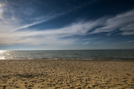 Empty, sandy beach by sunset under deep blue skyの写真素材