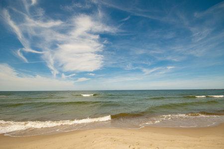 Empty, sandy beach and sea waves by sunny dayの写真素材