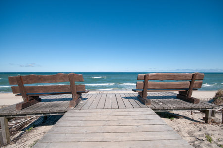 Empty wooden benches at a sea coast lineの写真素材