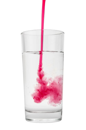 Cranberry syrup pouring into water glass on white backgroundの写真素材