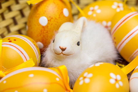 Bunny figure with yellow Easter eggs in a basket.の写真素材