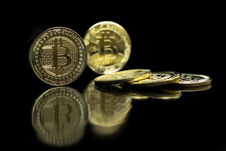 Bitcoin coins are laid on a reflecting surface on a black background and are mounted on their edges.の写真素材