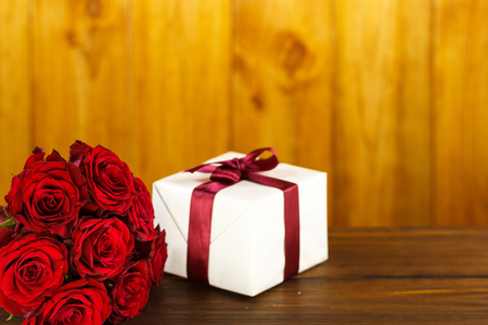 Red roses and gift box on brown wooden tableの写真素材