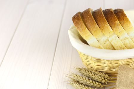 White sliced bread in a basket on the white wooden table.