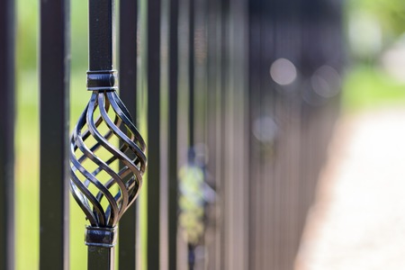 Black decorative metal fence, angular iron rods and curved upper part. Close-up of the decoration on...