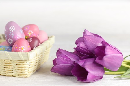 Purple tulips and easter eggs on a white wooden table
