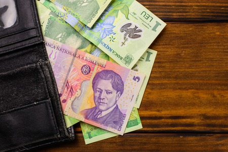 Various Romanian banknotes on a wooden table, 1-5 leu and a wallet. Europe Hungary.の写真素材