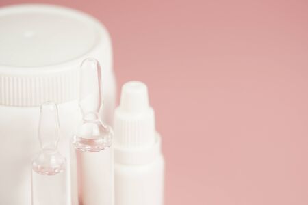 White medical pills and medical preparations in with bottles, glass ampoues,close-up on pink background. Closeup photo of medical preparations with copy spaes.の写真素材