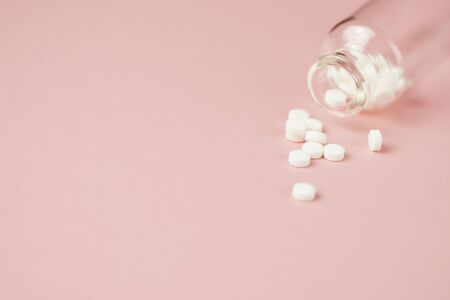 White medical pills in glass bottles,close-up on pink background. Closeup photo of medical preparations with copy spaes.の写真素材