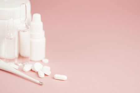 White medical pills and medical preparations in with bottles, glass ampoues,close-up on pink background. Closeup photo of medical preparations with copy spaes.の写真素材