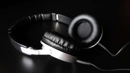 Black headphones isolated on a black background, close up.の写真素材