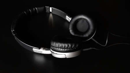 Black headphones isolated on a black background, close up.の写真素材