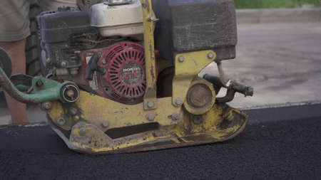 Vibratory asphalt paving machine HONDA on the sidewalk filmed close-up.Road works,pavement repair,hard work.Video clip.のeditorial素材