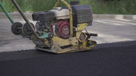 Vibratory asphalt paving machine HONDA on the sidewalk filmed close-up.Road works,pavement repair,hard work.Video clip.のeditorial素材