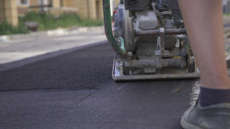 Vibratory asphalt paving machine on the sidewalk filmed close-up.Road works,pavement repair,hard work.Video clip.の写真素材
